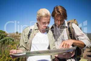Hiking couple walking on mountain terrain looking at map