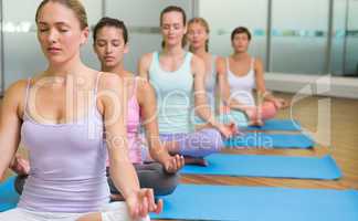 Yoga class in lotus pose in fitness studio