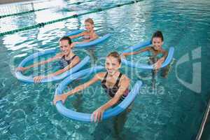 Fitness class doing aqua aerobics with foam rollers