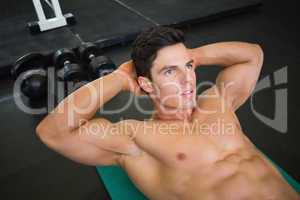 Muscular man doing abdominal crunches in gym