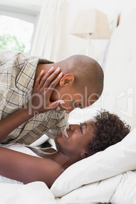 Intimate couple cuddling lying on their bed