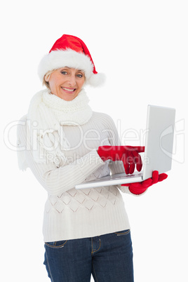 Festive woman using laptop smiling at camera