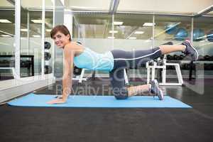 Fit smiling brunette doing pilates on exercise mat
