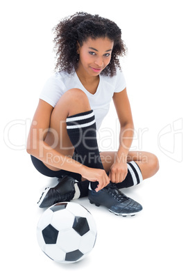 Pretty football player in white tying her shoelace