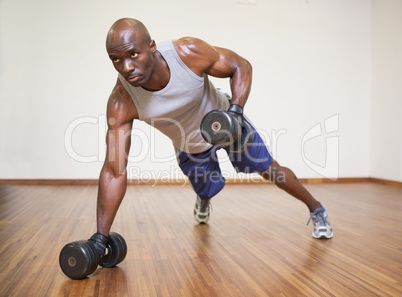 Muscular man doing push ups with dumbbells in gym