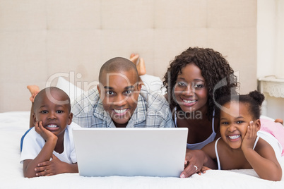 Happy family using laptop together on bed