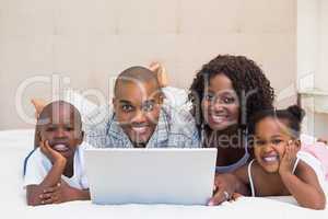 Happy family using laptop together on bed