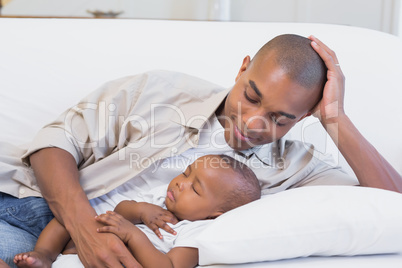 Happy young father with baby son on couch