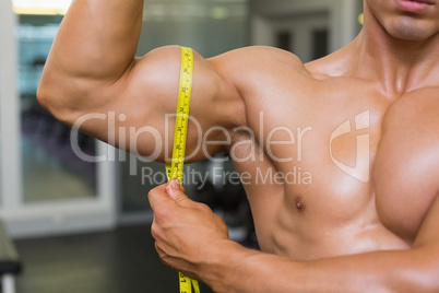 <id section of muscular man measuring biceps