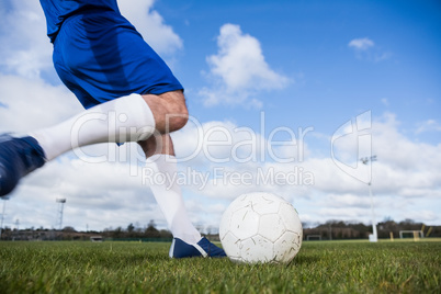 Football player in blue about to kick ball