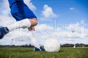 Football player in blue about to kick ball