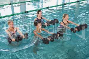 Female fitness class doing aqua aerobics with foam dumbbells