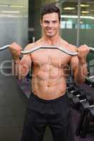 Smiling shirtless muscular man lifting barbell in gym