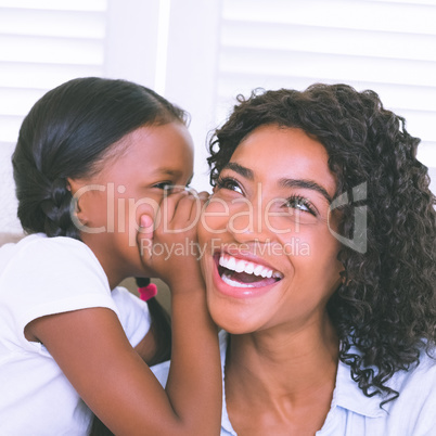 Pretty mother sitting on the couch with her daughter whispering