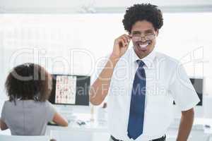 Young handsome editor smiling at camera with colleague working b