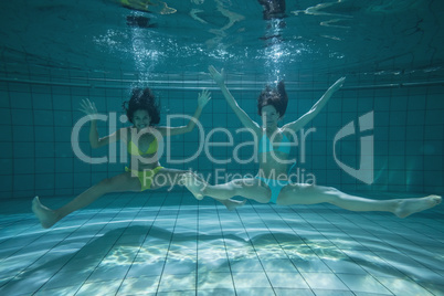 Pretty friends smiling and posing for camera underwater