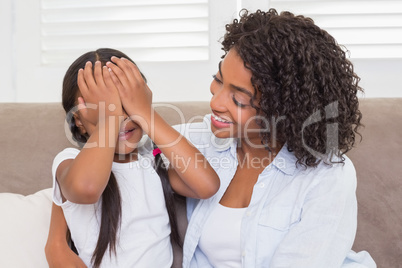 Pretty mother sitting on the couch with her daughter covering he