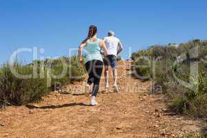 Fit couple running up mountain trail