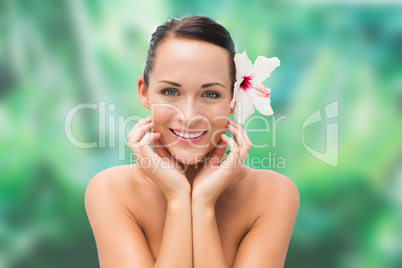 Beautiful nude brunette smiling at camera with flower in her hai