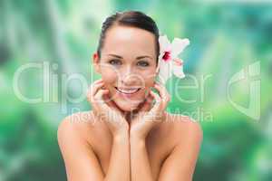 Beautiful nude brunette smiling at camera with flower in her hai