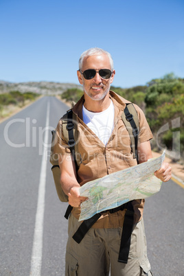 Handsome hiker holding map and smiling at camera