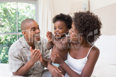 Happy couple on bed with baby daughter