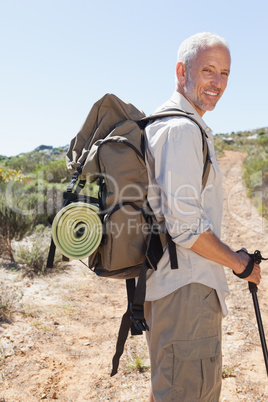Handsome hiker smiling at camera in the countryside