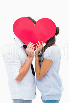 Couple covering their kiss with a heart