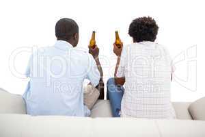Two sports fans sitting on the couch with beers
