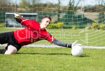 Goalkeeper in red saving a goal during a game