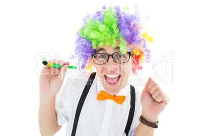 Geeky hipster wearing a rainbow wig holding party horn
