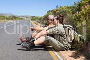 Hiking couple sitting on the side of the road