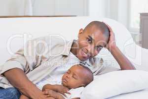 Happy young father with baby son on couch