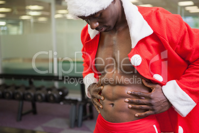 Macho man in santa costume looking at his abs