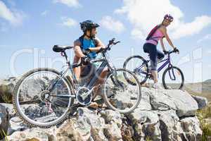 Fit cyclist couple taking a break on rocky peak