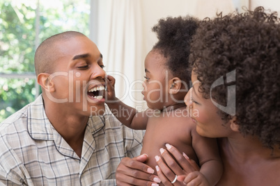 Happy couple on bed with baby daughter