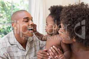 Happy couple on bed with baby daughter