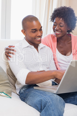 Cute couple relaxing on couch with laptop