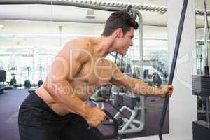 Shirtless muscular man using resistance band in gym