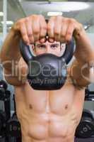 Muscular man lifting kettle bell in gym