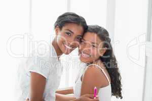 Pretty mother hugging her daughter smiling at camera