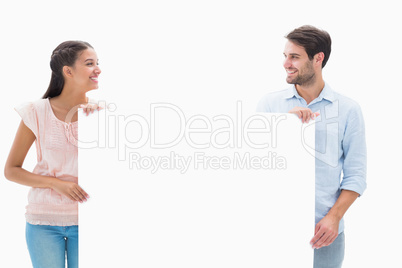 Attractive young couple smiling and holding poster