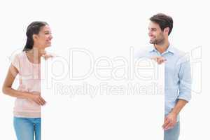 Attractive young couple smiling and holding poster