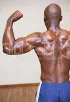 Rear view of shirtless muscular man flexing muscles