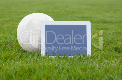 Football and tablet with blank screen on pitch Football and tablet with blank screen on pitch