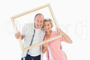 Older couple smiling at camera through picture frame