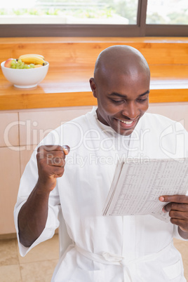 Happy man in bathrobe reading newspaper