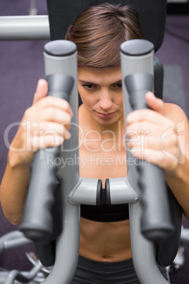 Serious brunette using weights machine for arms Serious brunette using weights machine for arms