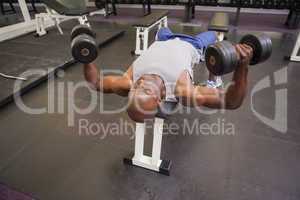 Muscular man exercising with dumbbells