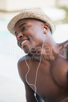 Shirtless man smiling and listening to music